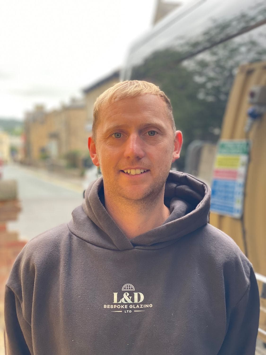 Luke Allan of L&D Bespoke Glazing, in a company hoodie beside the works van